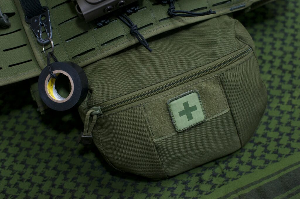 pexels-photo-6562586-6562586 Close-up of a green first aid kit pouch attached to military gear, highlighting preparedness.